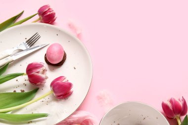 Paskalya yumurtalı masa ayarı ve pembe arka planda güzel laleler.