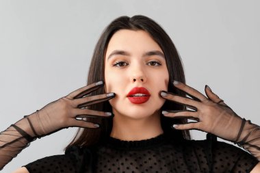 Gri arkaplanda kırmızı dudakları olan güzel genç bir kadın.