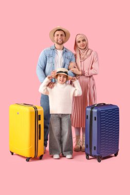 Pembe arka planda bavulları olan güzel Müslüman bir aile. Seyahat kavramı