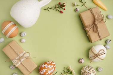 Paskalya yumurtalarından, çiçeklerden ve yeşil arka planda hediye kutularından yapılmış güzel bir çelenk.