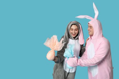 Mavi arka planda Paskalya hediyesi yumurtaları olan tavşan kostümlü güzel bir çift.