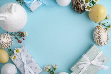 Paskalya yumurtalarından, tavşan figüründen ve mavi arka planda hediye kutularından yapılmış şık bir çelenk. Yakın plan.