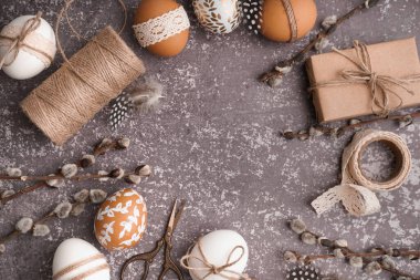 Paskalya yumurtaları, söğüt dalları ve gri arka planda hediye kutusu.