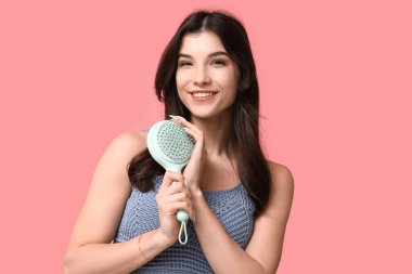 Pembe arka planda mavi saç fırçası olan güzel bir genç kadın.