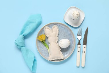 Paskalya yumurtası, oyuncak tavşan ve mavi arka planda sarı lale.