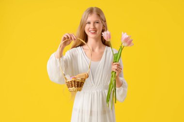 Paskalya sepeti tutan genç ve güzel bir kadın. Sarı arka planda spa aksesuarları ve lale çiçekleri var.