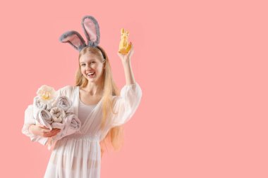 Tavşan kulaklı güzel bir kadın temiz havlular ve pembe arka planda Paskalya tavşanı tutuyor.
