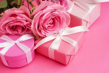 Hediye kutuları ve pembe arka planda güzel güller.