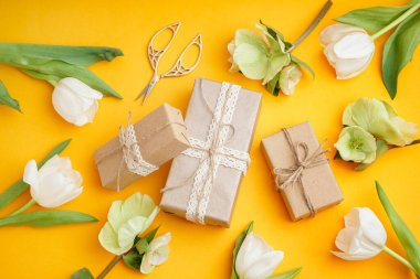 Hediye kutuları ve sarı arka planda güzel çiçekler.