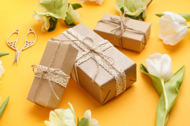 Hediye kutuları ve sarı arka planda güzel çiçekler.