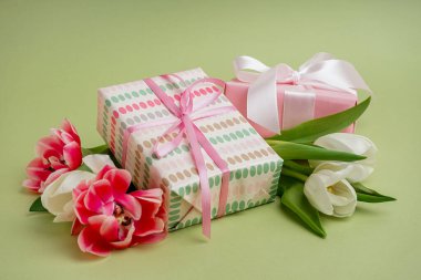 Hediye kutuları ve yeşil arka planda güzel laleler.