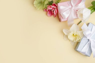 Hediye kutuları ve sarı arka planda güzel çiçekler.