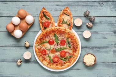 Tavşan kulaklı Paskalya pizzası, gri ahşap arka planda yumurta ve peynir.