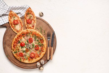 Lezzetli Paskalya pizzası, tavşan kulaklı ve beyaz arka planda çatal bıçaklı.