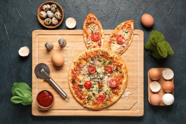 Tavşan kulaklı lezzetli Paskalya pizzası, siyah arka planda yumurta ve sos.