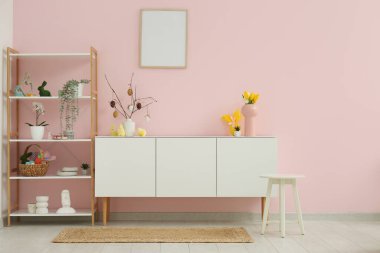 Beyaz çekmeceler ve şık oturma odasında Paskalya dekoru olan raf ünitesi.