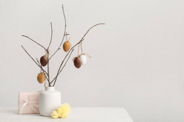 Seramik vazoda Paskalya yumurtaları, civciv ve beyaz duvarın yanında hediye.