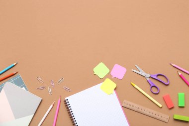 Kahverengi arka planda defter ve kırtasiye malzemeleri. Üst görünüm