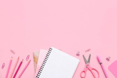 Not defteri, kalem ve makas pembe arka planda. Üst görünüm