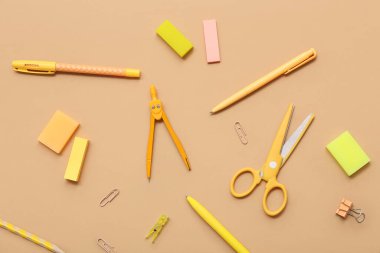 Bej arka planda makas, ataç ve kalemler. Üst görünüm