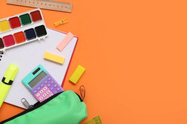 Turuncu arka planda farklı kırtasiye malzemeleri. Üst görünüm