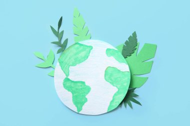 Mavi arka planda yeşil yaprakları olan kağıt gezegen Dünya. Dünya günü kutlaması.