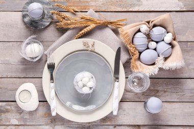 Paskalya kutlaması için şık bir masa. Gri ahşap arka planda boyanmış yumurtalar. Üst görünüm