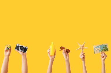 Küçük kilidi olan kadın eller, fotoğraf makinesi, güneş kremi, güneş gözlüğü, denizyıldızı ve seyahat hediye çeki sarı arka planda. Seyahat kavramı.