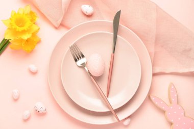 Pembe arka planda boyanmış Paskalya yumurtaları ve narsist çiçeklerle güzel bir sofra.