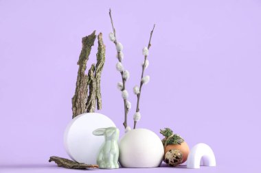 Paskalya yumurtaları, oyuncak tavşancık ve leylak arkaplanlı söğüt dallarıyla dekoratif podyumlar