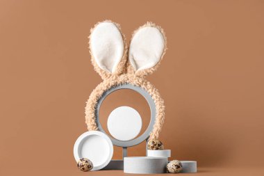 Paskalya yumurtaları ve kahverengi arka planda tavşan kulakları olan dekoratif podyumlar.