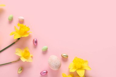 Sarı narsisli ve pembe arka planda Paskalya yumurtaları.
