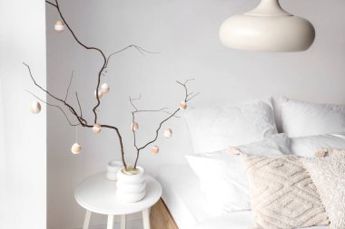 Vazo, ağaç dalları ve Paskalya yumurtaları açık yatak odasındaki masada.