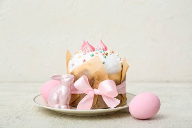 Plate with tasty Easter cake, eggs and toy bunny on white background