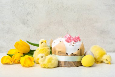 Beyaz arka planda sarı laleler ve piliçlerle lezzetli Paskalya pastası.