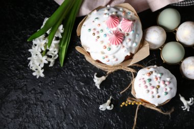 Tatlı Paskalya pastaları, güzel çiçekler ve siyah arka planda yumurtaları olan tutucu.