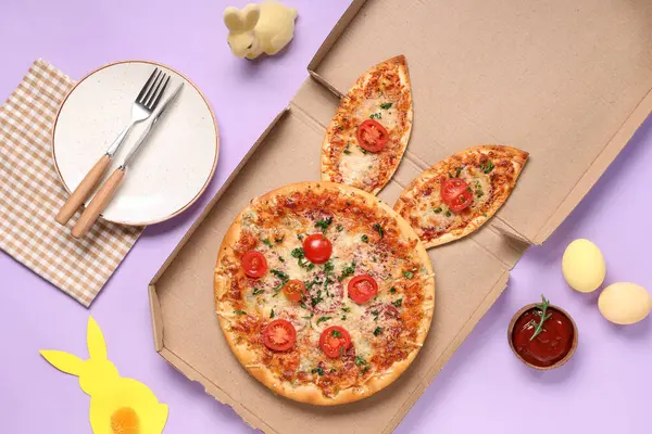 Paskalya pizzası karton kutusunda kulakları, yumurtaları ve çatal bıçakları var.