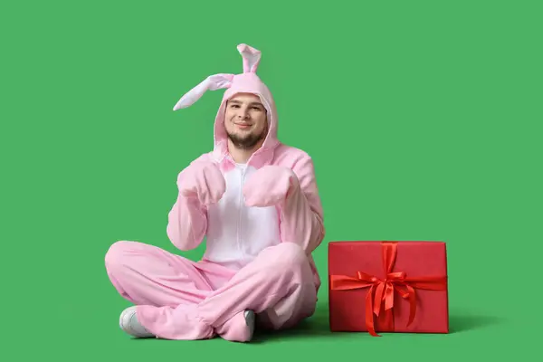 身穿兔子服装 头戴礼品盒的年轻人坐在绿色背景上 复活节庆祝活动 — 图库照片