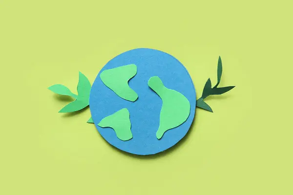 Paper planet Earth with green paper leaves on green background. Earth Day celebration.