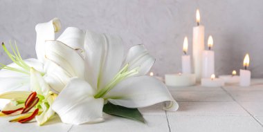 Zambak çiçekleri ve yanan mumlar. Cenaze konsepti