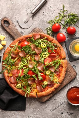 Tahta tahtada domatesli lezzetli pizza ve gri arka planda roka.