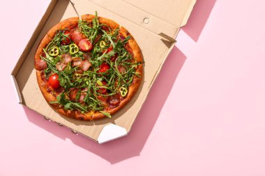 Üzerinde domates ve roka olan lezzetli pizzalardan oluşan karton bir kutu.