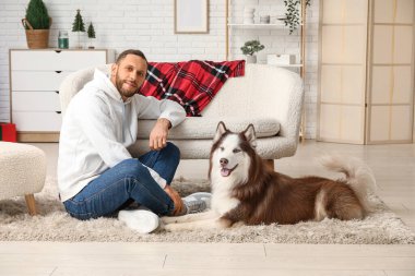 Evde sevimli köpekli yakışıklı bir genç adam.