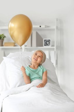 Kemoterapiden sonra klinikte yatan balonla küçük bir Asyalı kız. Çocukluk kanseri farkındalığı