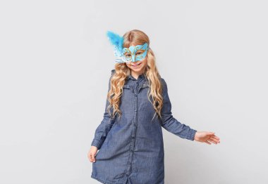 Hafif arka planda karnaval maskesi takan komik küçük kız.