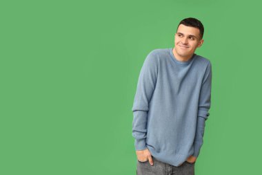 Yeşil arka plandaki yakışıklı, utangaç genç adam.