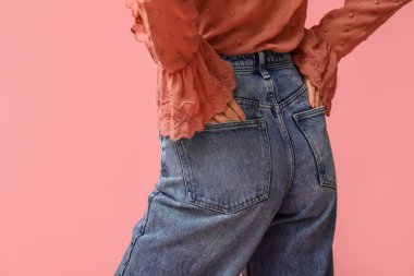 Pembe arka planda şık kotlu güzel bir Asyalı kadın.