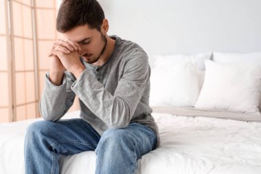 Genç adam yatak odasında dua ediyor.