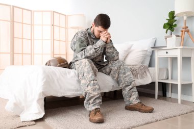 Genç erkek asker yatak odasında dua ediyor.