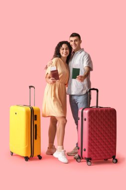 Pembe arka planda pasaportları ve bavulları olan iki turist.